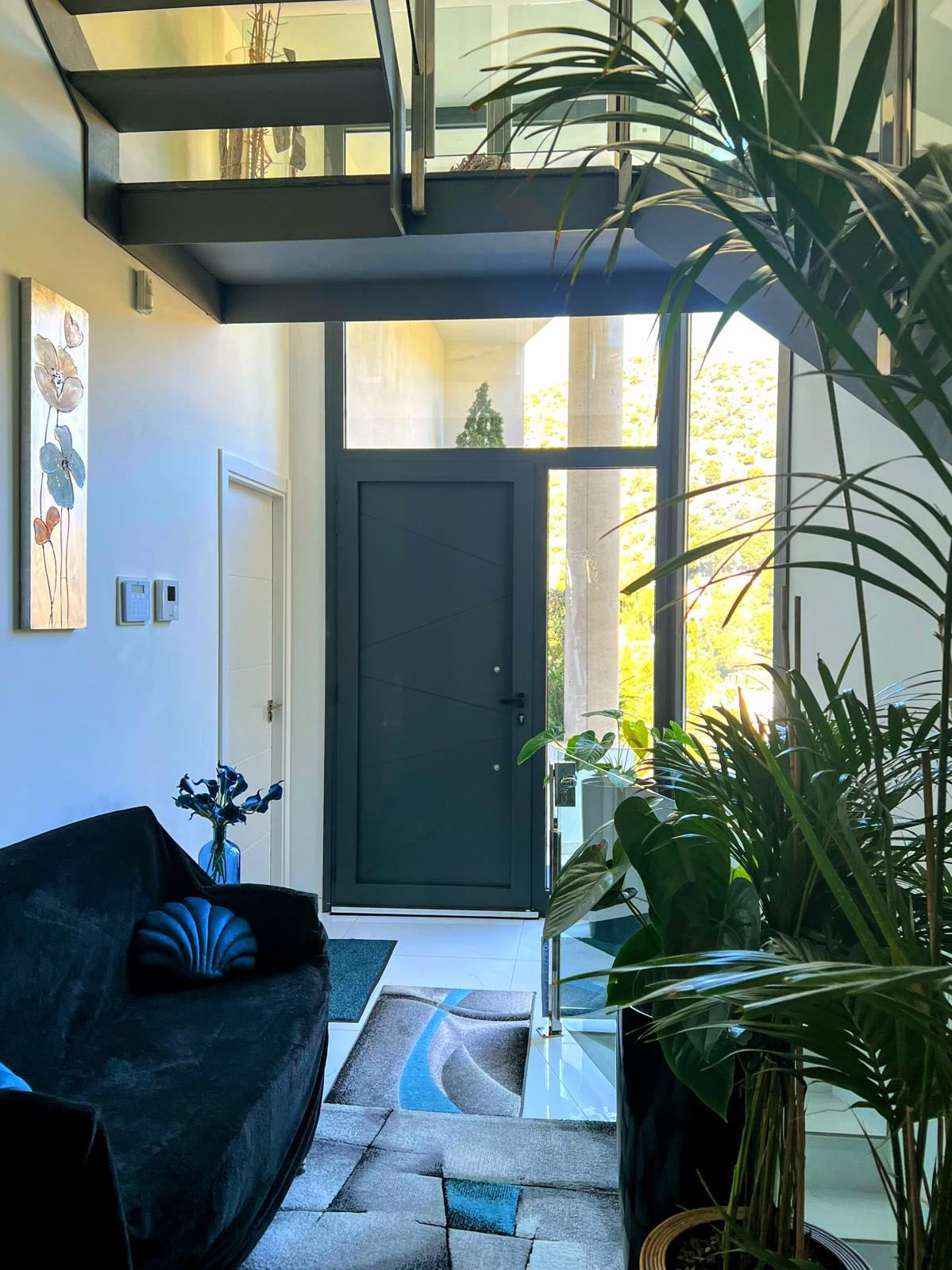 Entrée élégante de l'Appartement Bambou avec canapé bleu et plantes tropicales