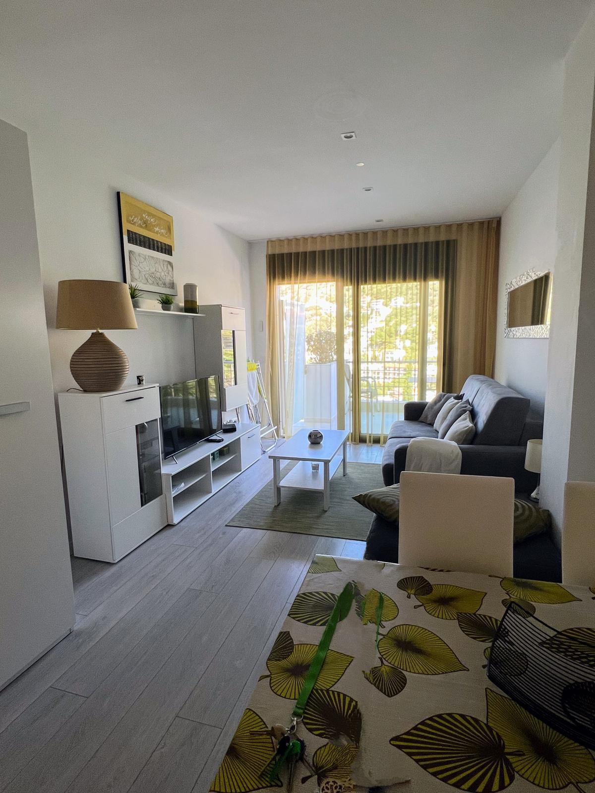 Salon lumineux de l'Appartement Bambou avec canapé gris et vue sur la terrasse
